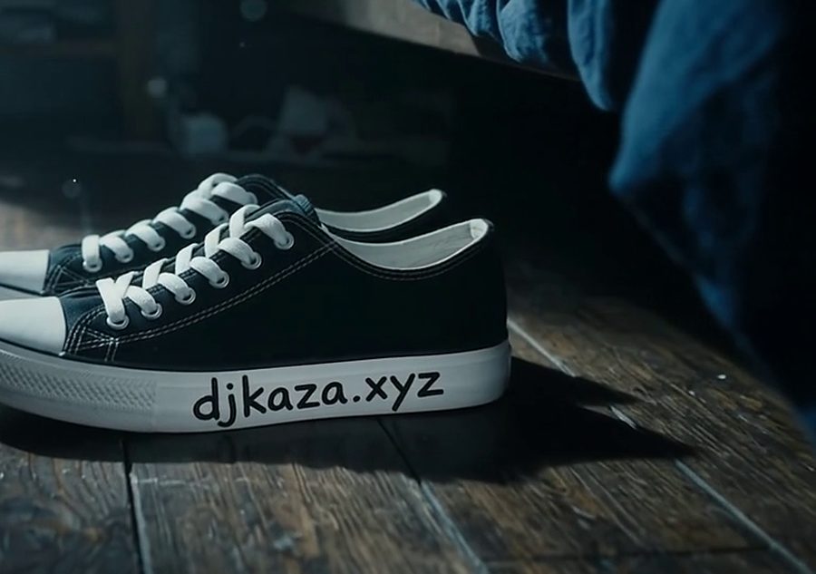 Sneakers by the bed at night with djkaza.xyz written on the sole